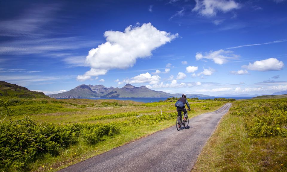 A cyclist going down a single track road with views to other islands in the distance