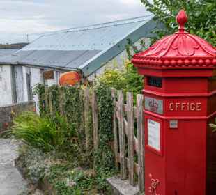 The famous red Royal Mail post boz and small lane to the post office building.