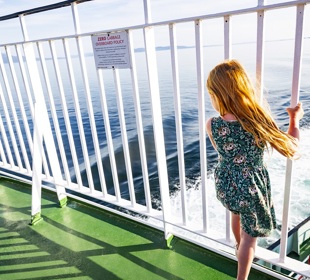 Girl standing at railings looking out to sea