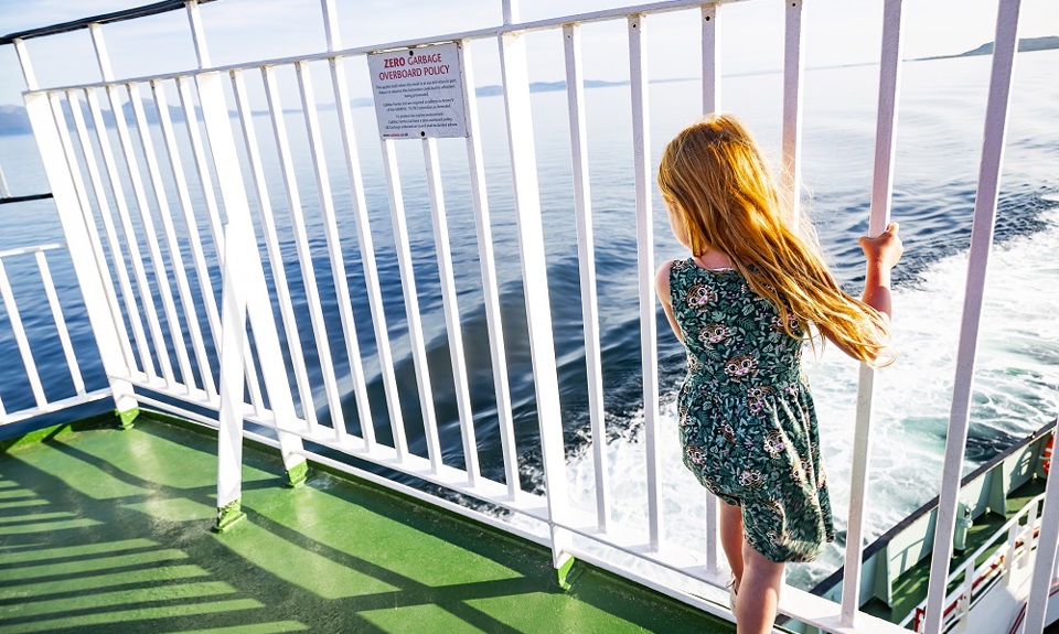 Girl standing at railings looking out to sea