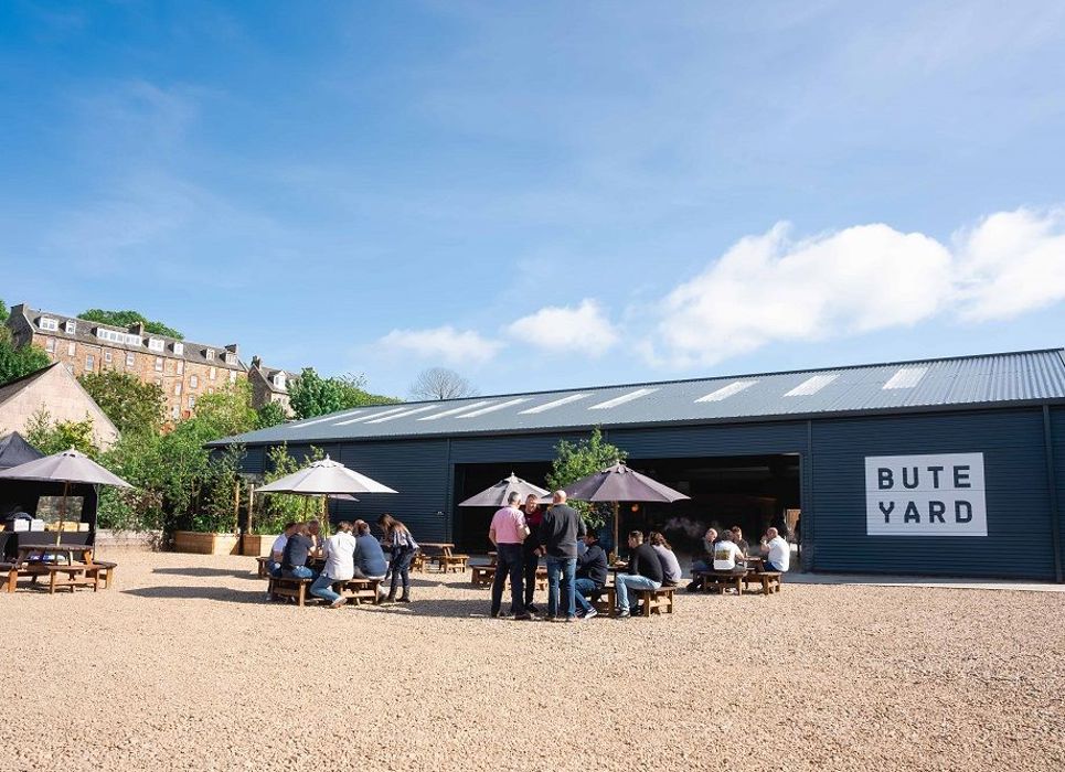 People sitting outside on tables at Bute Yard enjoying artisan local products