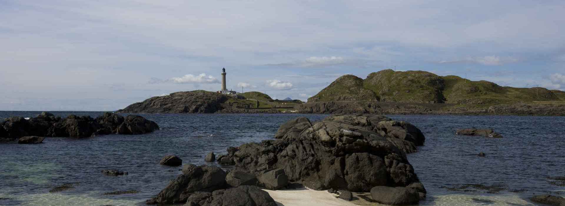 A view to Ardnamurchan Point and the lighthouse from a sandy beach.