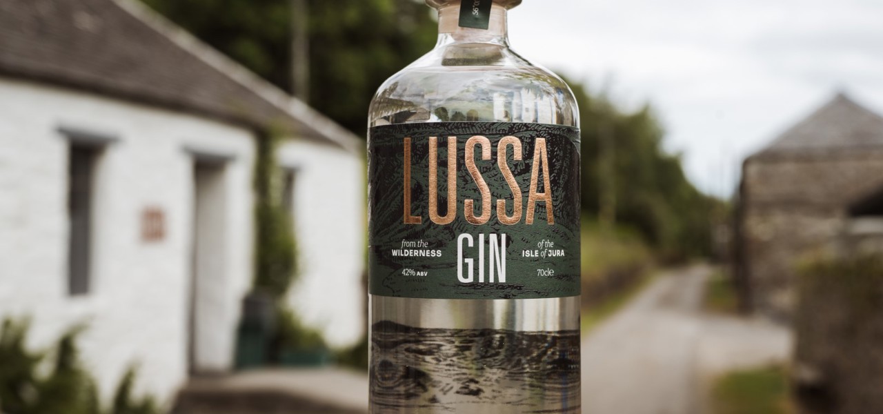 Someone holding a bottle of gin with the stables in the background