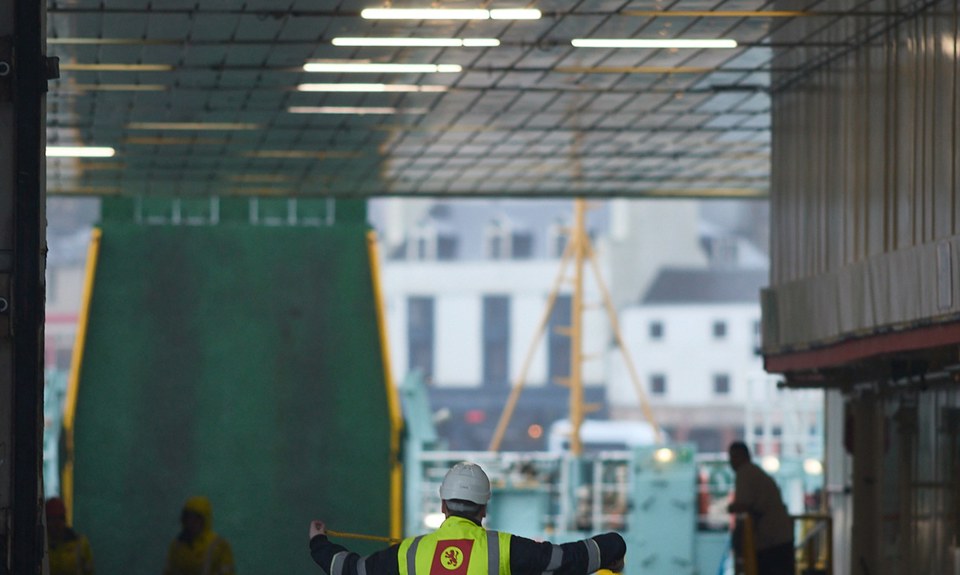 Crew member directing vehicle loading operations on board a CalMac ferry car deck.