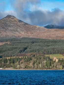 Goatfell, the highest peak on Arran, with woodland and water in the foreground.