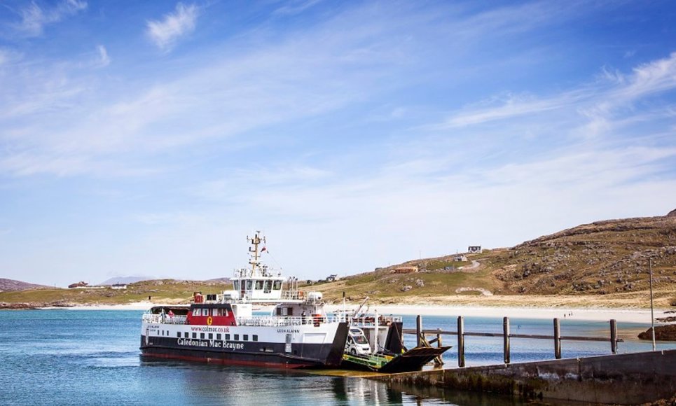 CalMac ferry MV Loch Alainn at Eriskay slipway on a bright day. Beach, a gentle hill and blue sky behind the ferry.