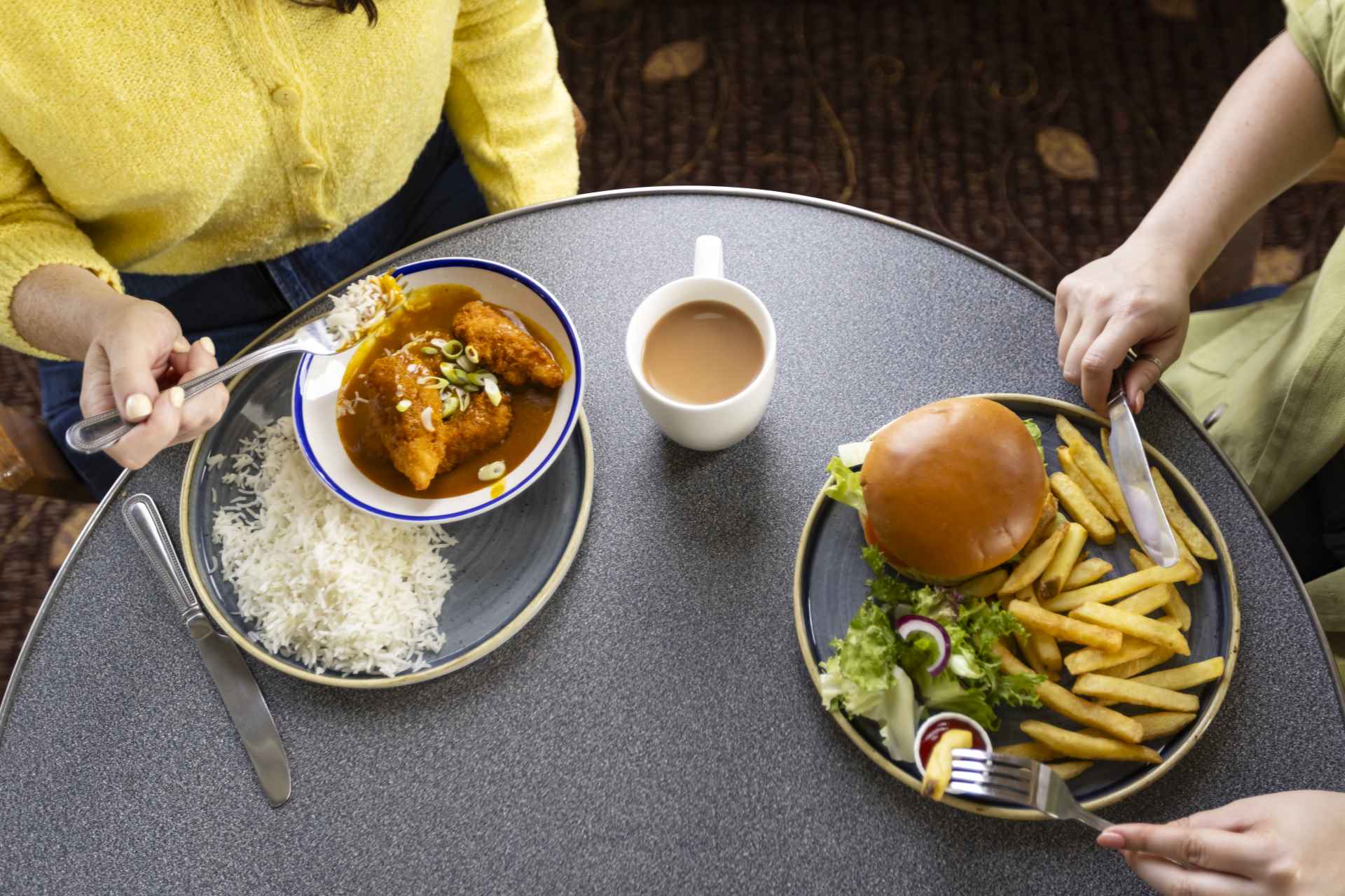 Two people enjoying meals at a table onboard a CalMac ferry.