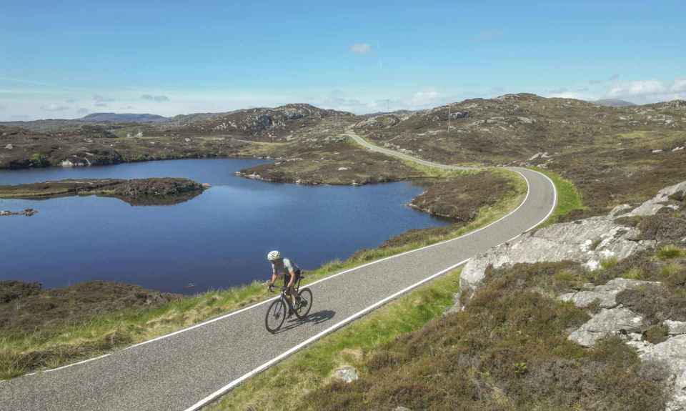 A cyclist riding on a single track road through the rocky Barra landscape.