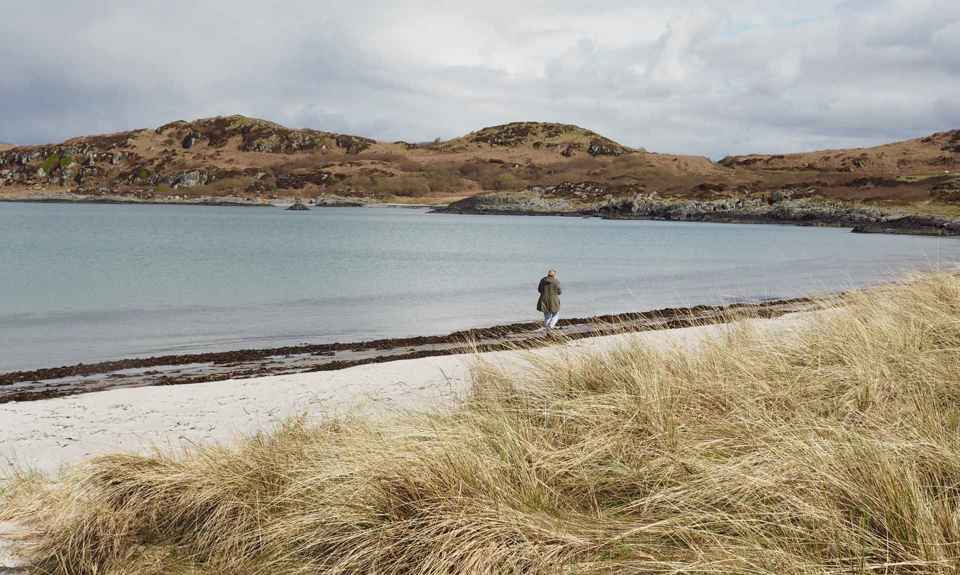 A person wandering along an empty beach on the isle of Gigha