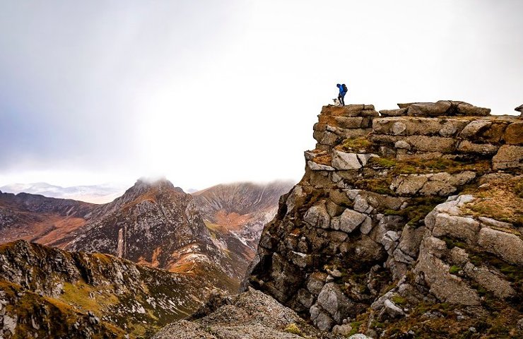 A climber and his dog up on a mountainous ridge on Goatfell, Arran