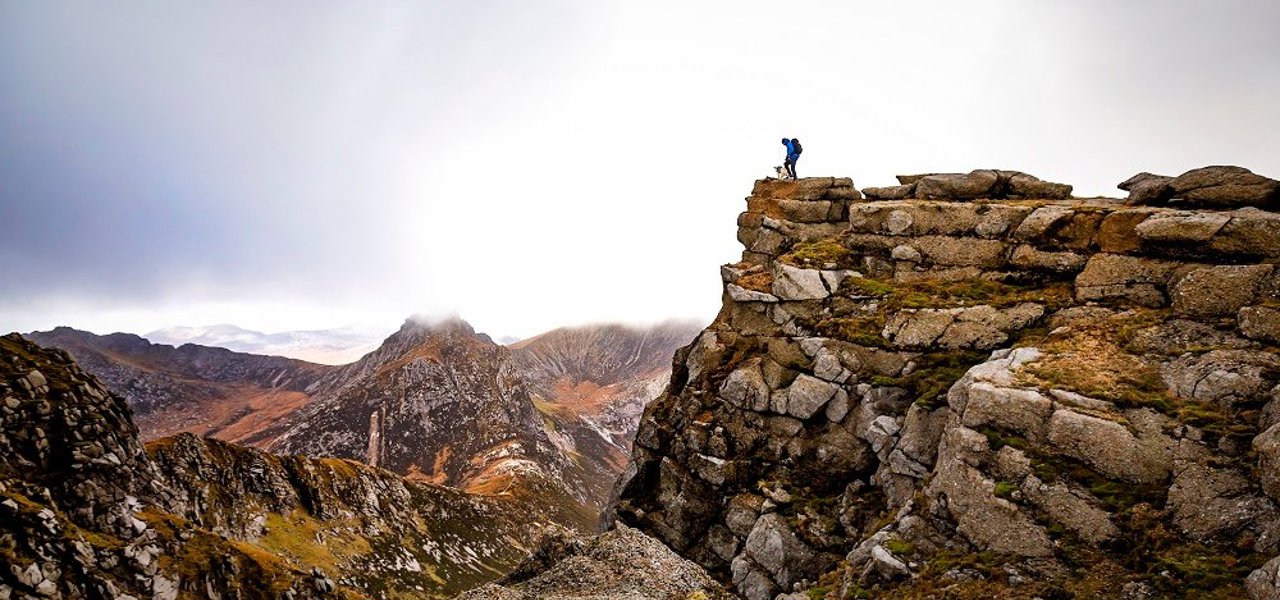 A climber and his dog up on a mountainous ridge on Goatfell, Arran