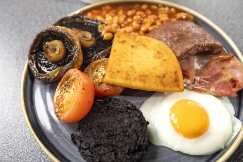 a plate of CalMac's big breakfast including bacon, slice sausage, egg, potato scone, black pudding, beans, mushrooms and a tomato