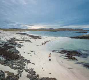 An aerial view of a person walking on Cliad Bay on Coll at sunset.