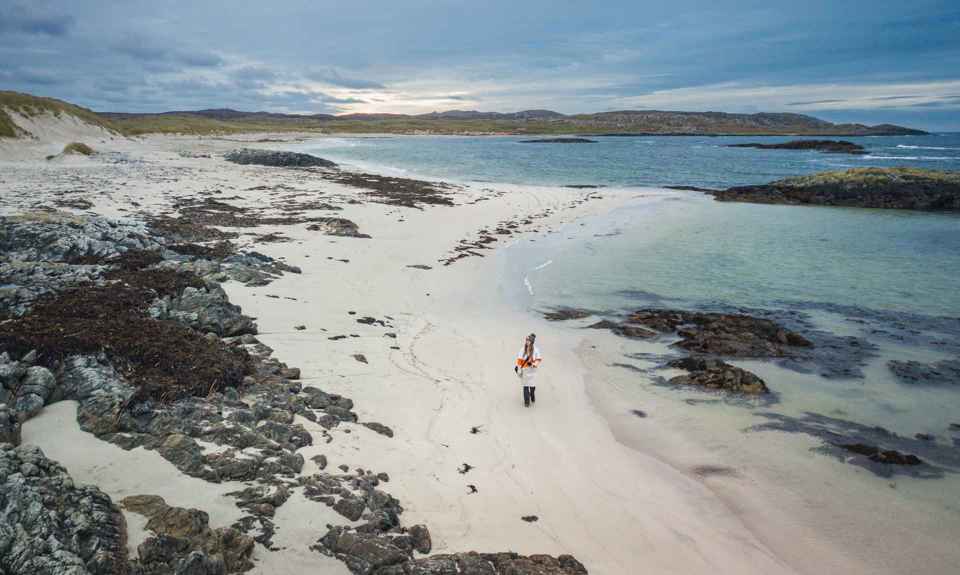 An aerial view of a person walking on Cliad Bay on Coll at sunset.
