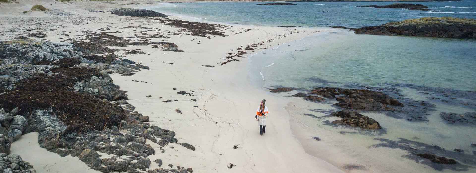 An aerial view of a person walking on Cliad Bay on Coll at sunset.