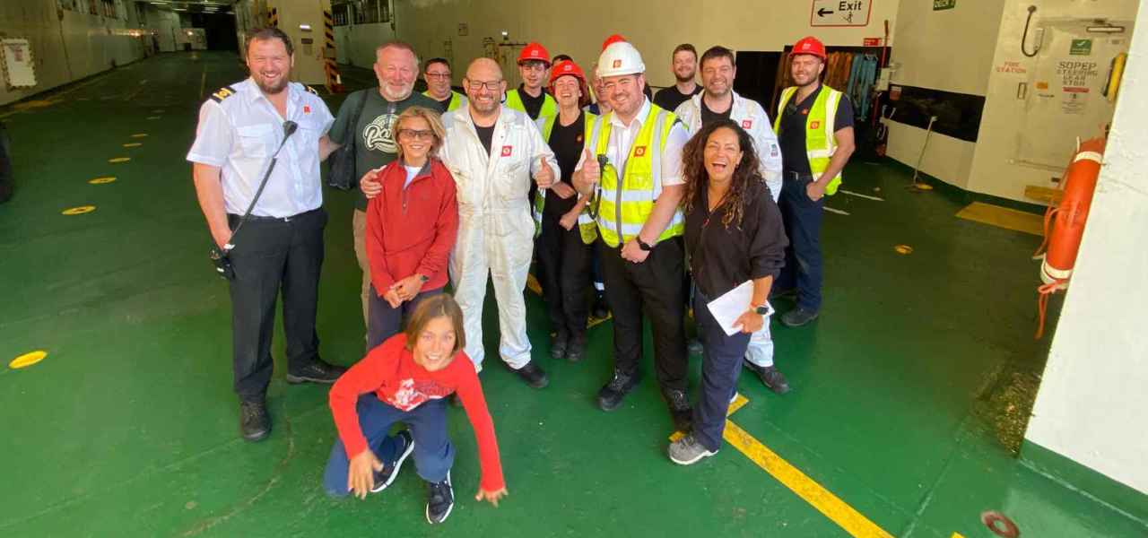 Image of the crew of the CalMac MV Isle of Lewis on an empty car deck, with customers they supported.