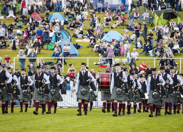 A Scottish Pipe Band marching in Highland dress with there bagpipes and drums