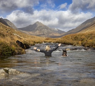 two female swimmers in Glen Rosa (Arran). One has a black wet suit with her hands in the air