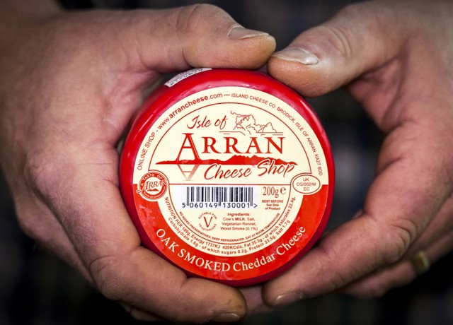 A round packet of Arran cheese being held in two hands