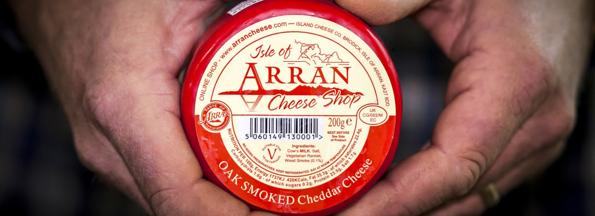 A round packet of Arran cheese being held in two hands