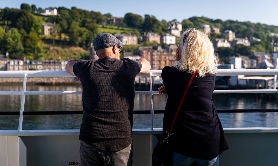 Two people standing looking over the ferry railings to the mainland