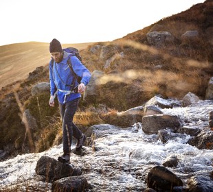 man walking down stones on Glen Rosa with the water from the stream flowing down past him