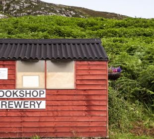 A wooden hut with signage point to the Bookshop and Brewery