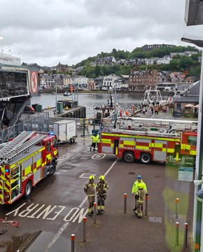 Fire and rescue vehicles positioned beside a CalMac ferry at Oban harbour during an emergency response exercise or incident.
