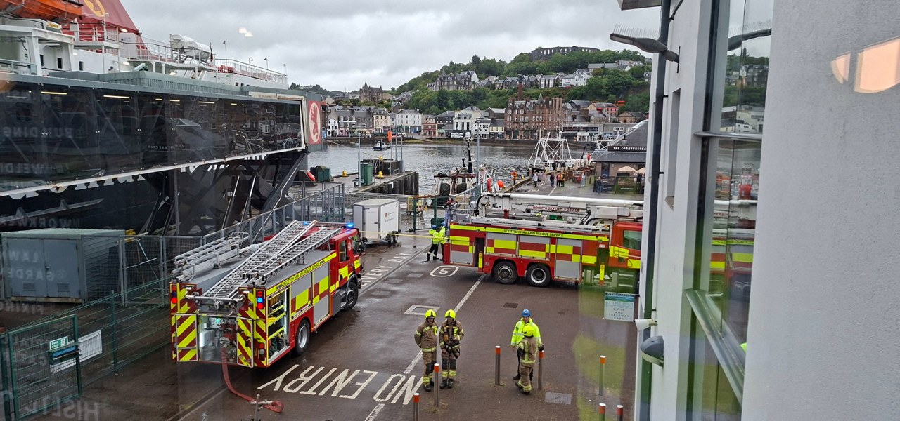Fire and rescue vehicles positioned beside a CalMac ferry at Oban harbour during an emergency response exercise or incident.