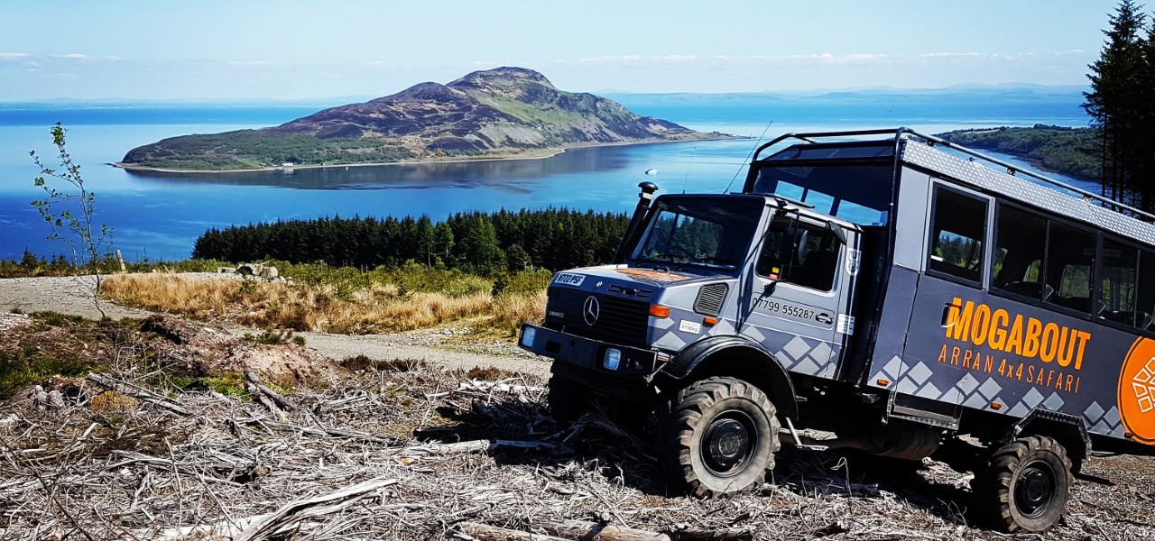 Mogabout van sitting on a hill with the water and holy isle in background