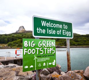 A welcome to Eigg sign with the rocky Sgurr of Eigg in the background