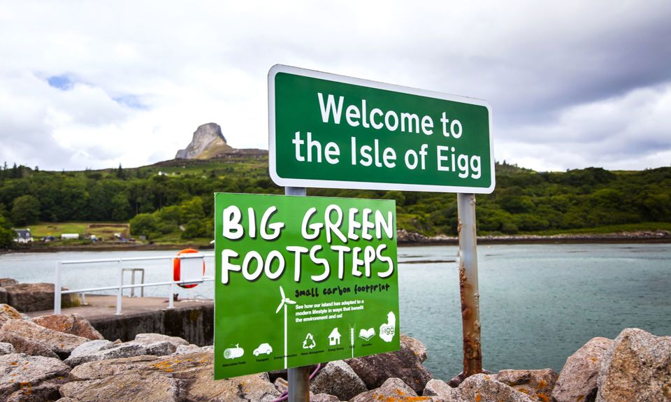 A welcome to Eigg sign with the rocky Sgurr of Eigg in the background