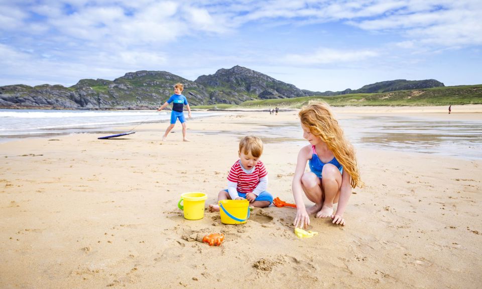 Children at the beach building sandcastles with yellow buckets and spades
