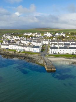 Aerial drone view of the white coloured houses of Port Charlotte and the island coastline