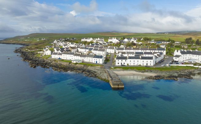 Aerial drone view of the white coloured houses of Port Charlotte and the island coastline