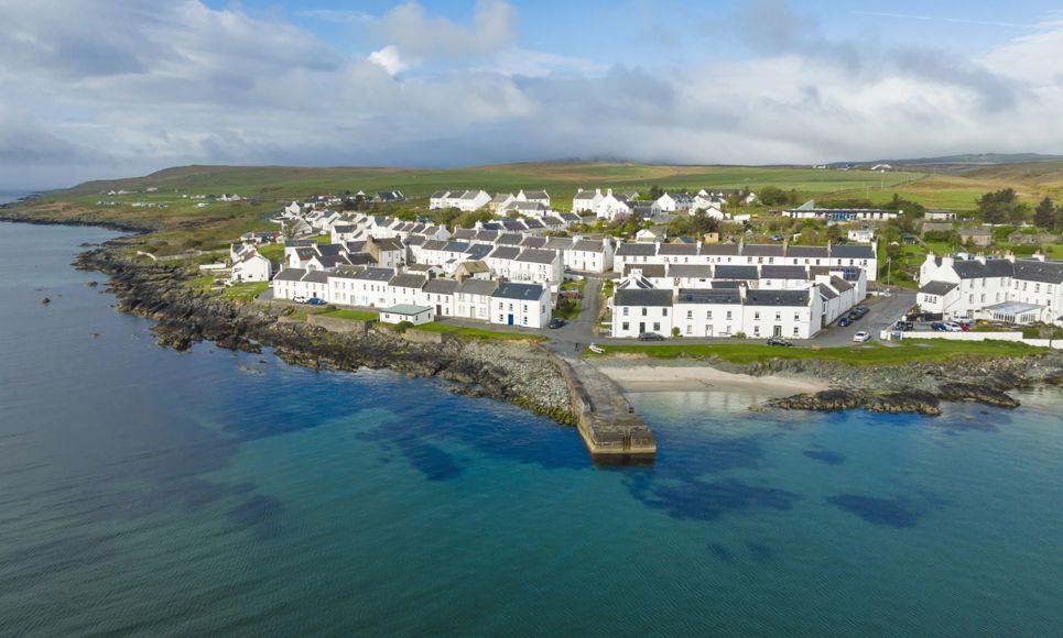 Aerial drone view of the white coloured houses of Port Charlotte and the island coastline