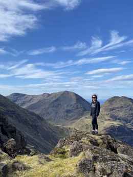 A walker standing at the peak of the Rum Cuillin Traverse on Rum.