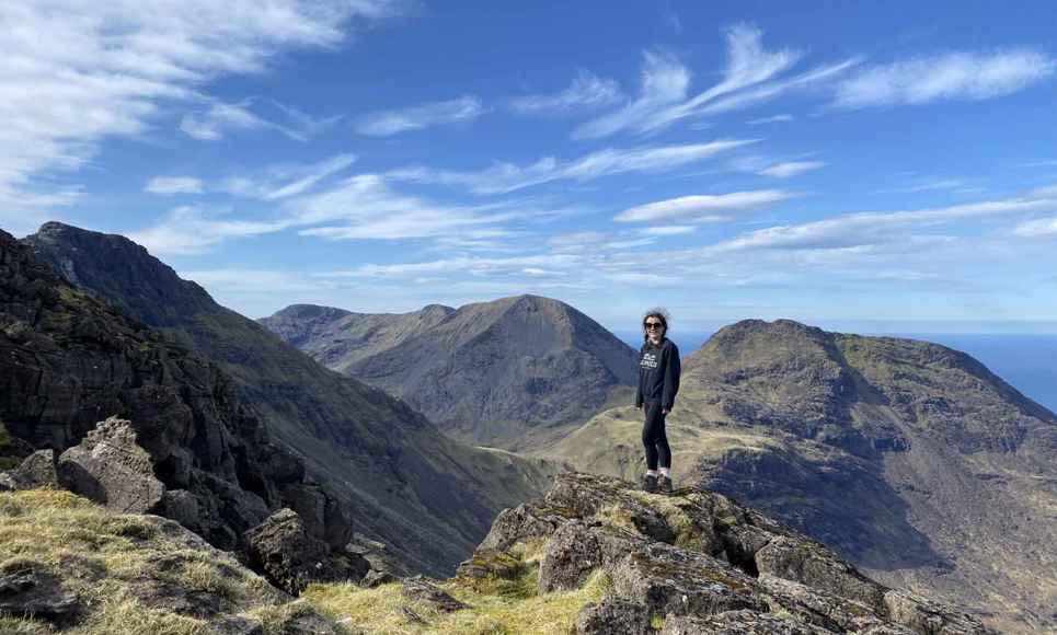 A walker standing at the peak of the Rum Cuillin Traverse on Rum.