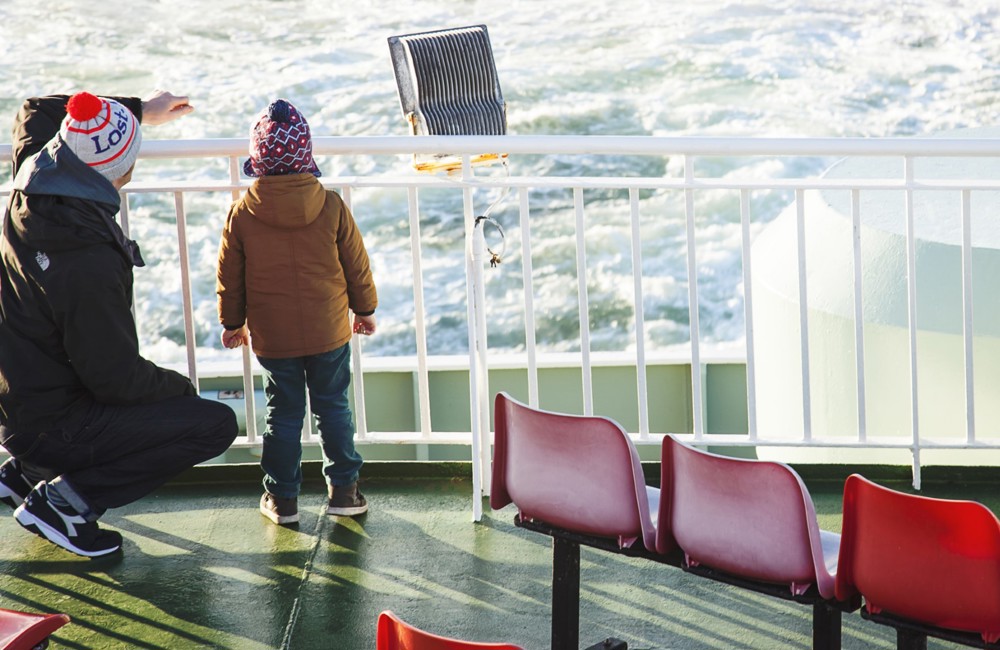 little boy and his dad on the boat deck looking out to sea