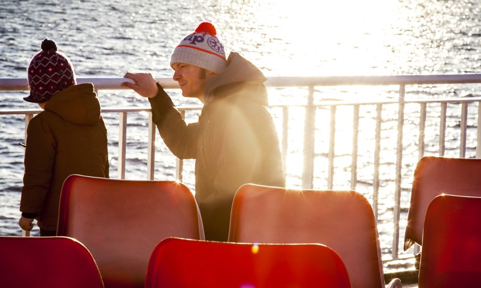 little boy and his dad looking out to sea from the boat deck with the sunset in the background