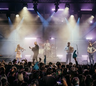 A band performing on stage with crowd cheering them on