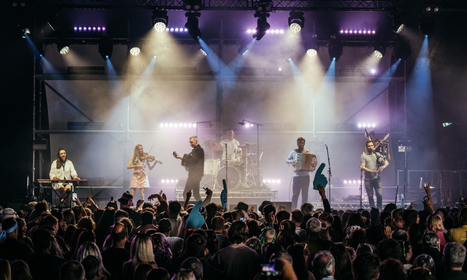 A band performing on stage with crowd cheering them on