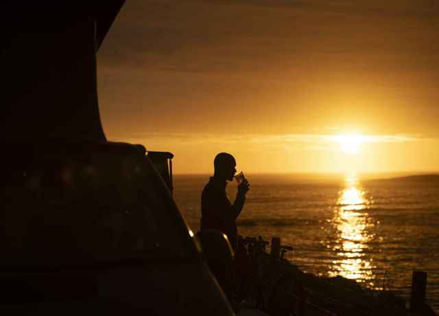 Sunset on Barra, with a person enjoying a drink outside