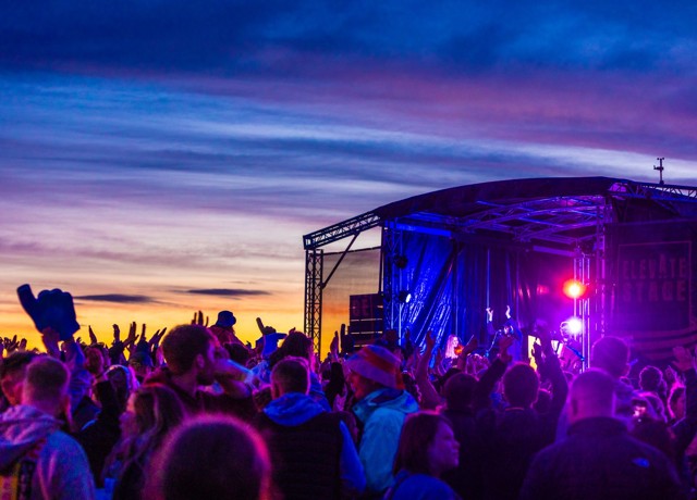 festival gooers facing the stage under a purple light