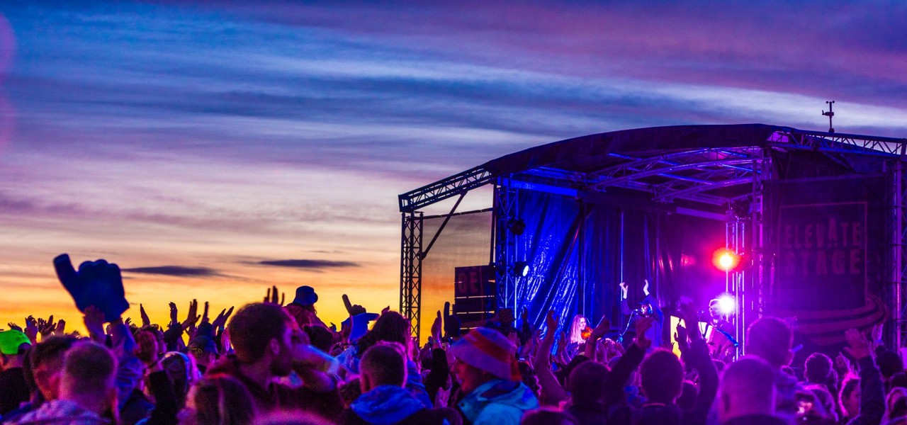 festival gooers facing the stage under a purple light