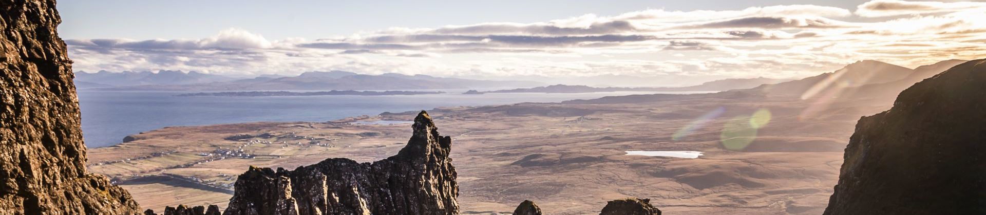 Hillwalkers resting with a view of mountain peaks and coastline, and across the water to the mainland from the Isle of Skye