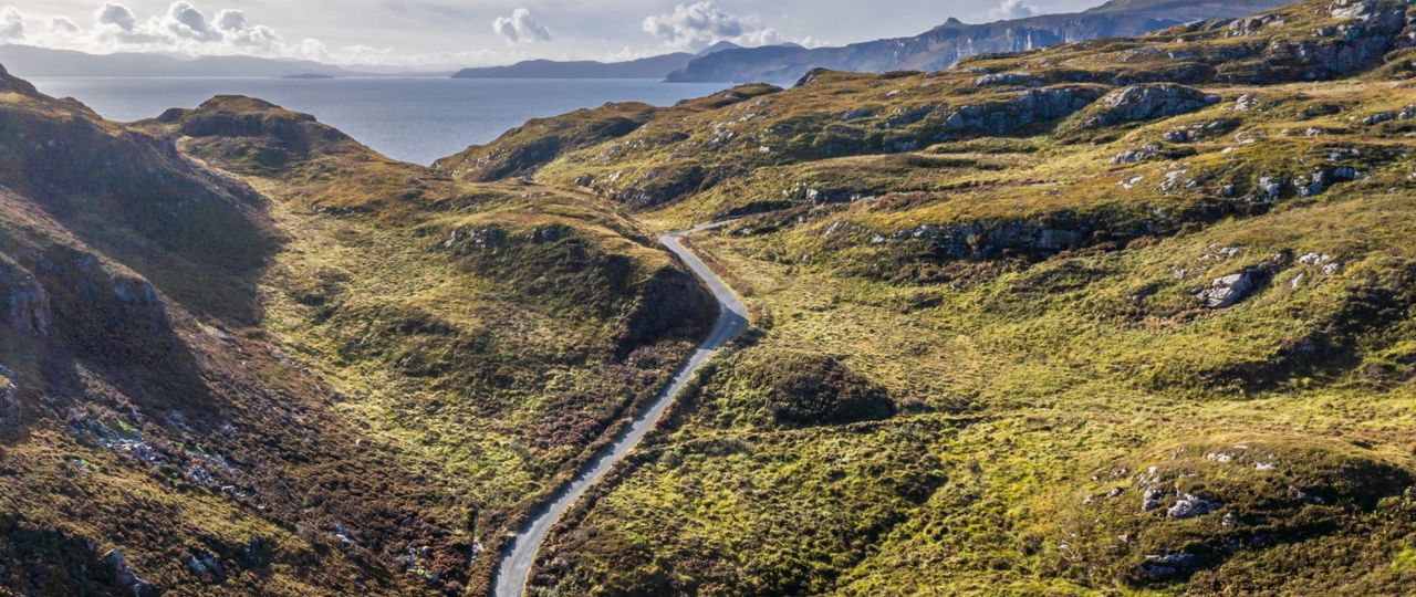 An aerial view of Calums road winding its way up the hilly landscap3 of Raasay.
