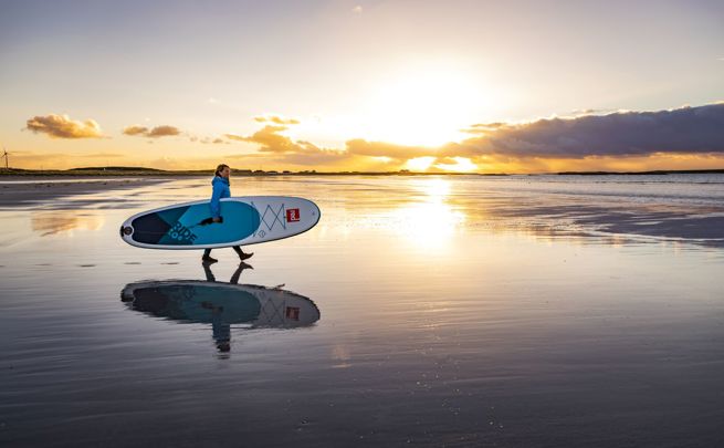 A Stand up paddle boarder on the beach at sunset, Tiree