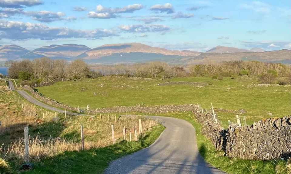 A winding single track road, with hills in the background, Lismore.