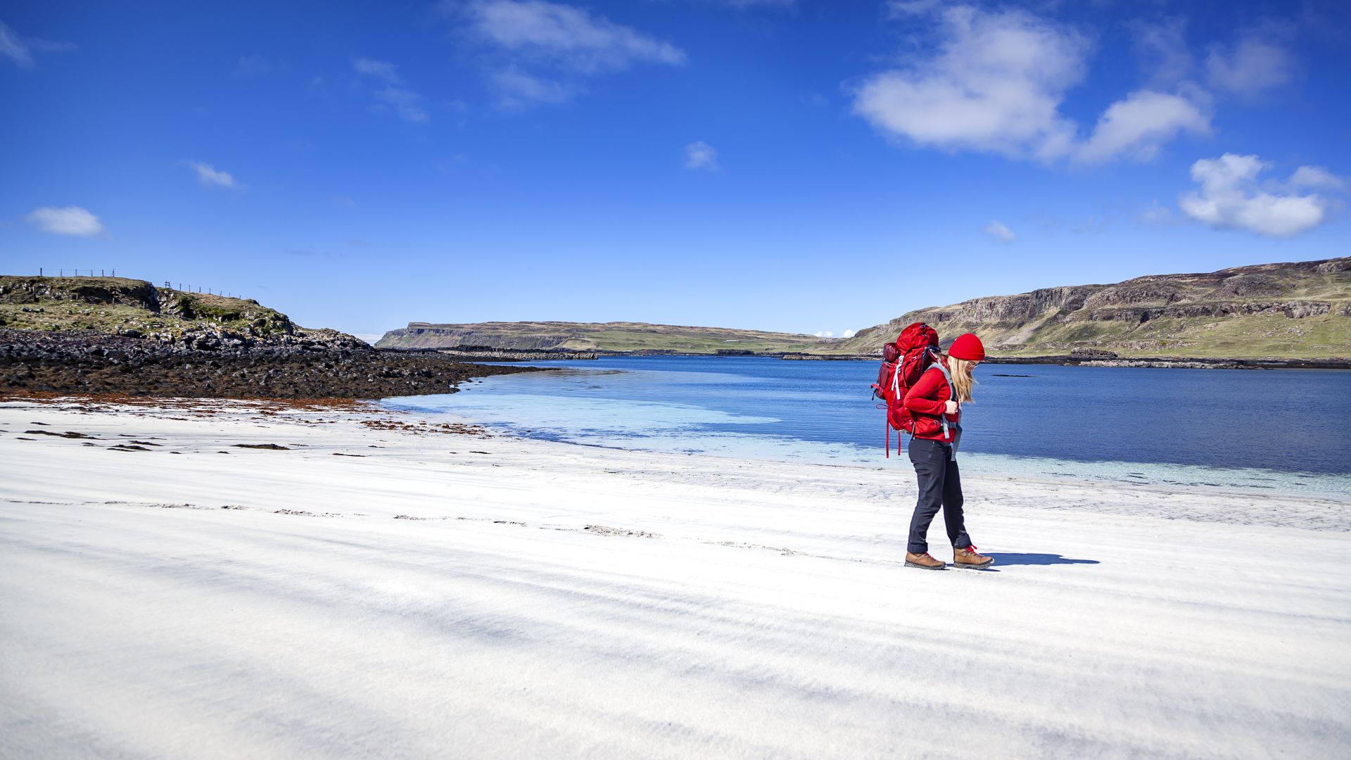 A walker on a beautiful sandy beach under a blue sky